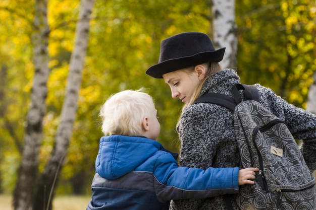 Maman et son fils sont assis dans la forêt d'automne et communiquent. Vue arrière