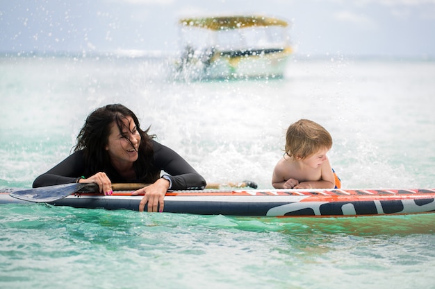 Maman et son fils surfent dans l'océan sur le tableau noir