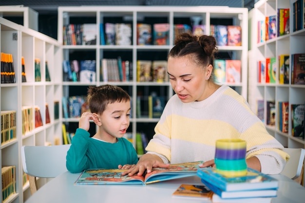 Maman et son petit enfant le fils d'âge préscolaire lisent ensemble des livres pour enfants