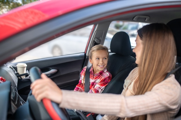 Maman souriante assise au volant, regardant sa fille