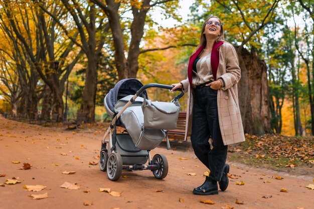 Maman souriante avec poussette de bébé dans le parc