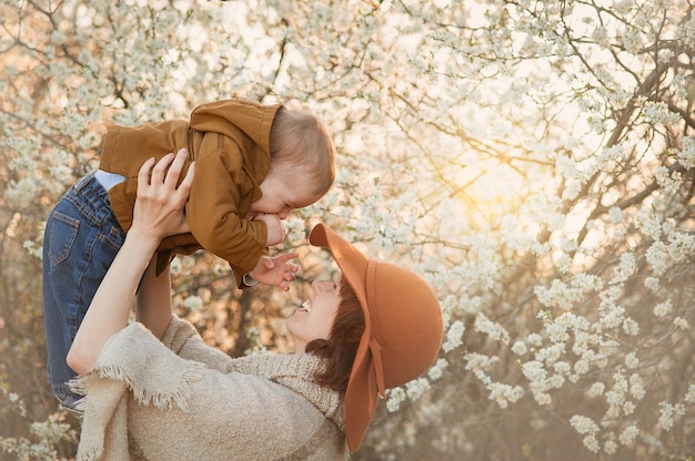 Maman tient le bébé sur fond d'arbres en fleurs