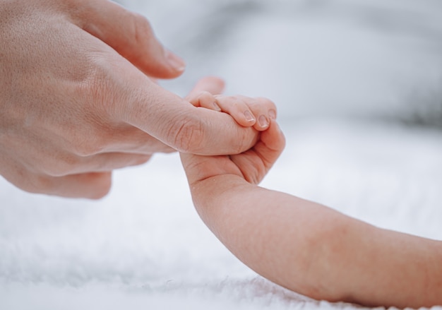 Maman tient le nouveau-né par la main