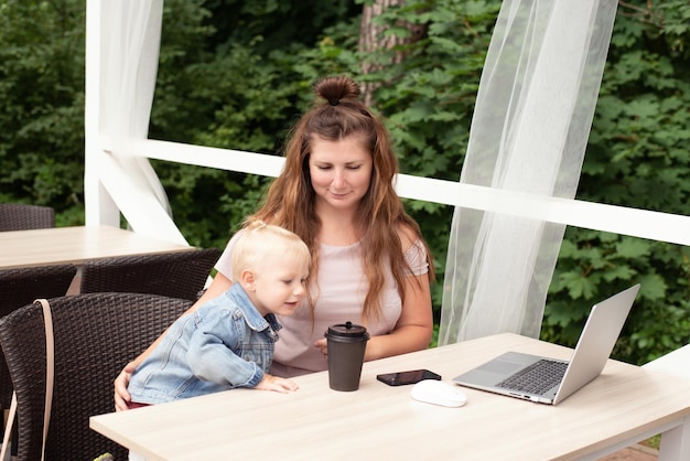 Maman travaille sur un ordinateur portable dans un café, l'enfant interfère avec le travail et la communication, un endroit pour copier