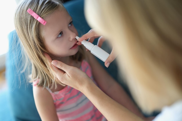 Maman vaporise le nez du bébé avec un spray