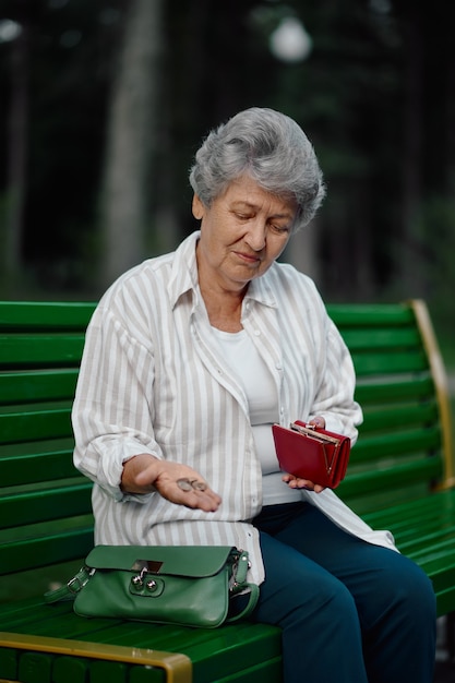 Mamie montre une bagatelle dans son portefeuille dans un parc d'été