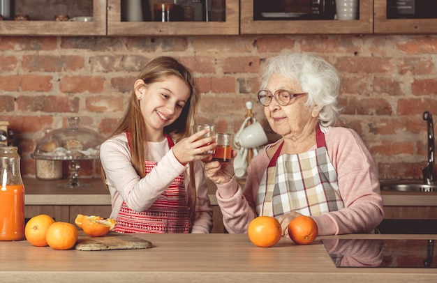 Mamie avec petite-fille dégustation de jus d'orange à la cuisine