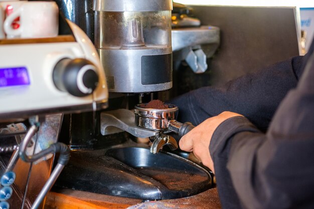 Man Barista faisant de la poudre de mouture de café sur une machine à café