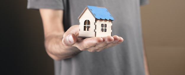 Man holding house sur fond marron