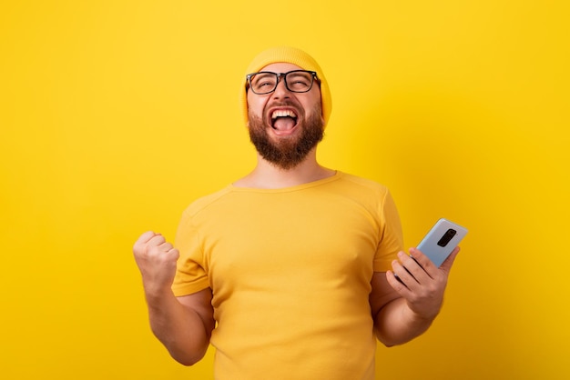 Man holding phone sur fond jaune, concept gagnant