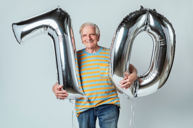 Photo man holding silver balloons pour son 70e anniversaire