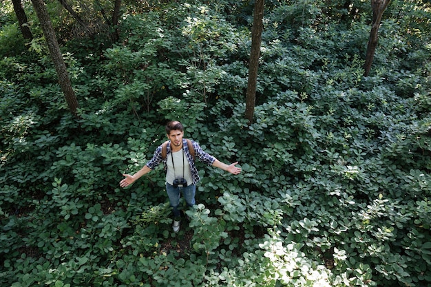 Man in forest avec jumelles et sac à dos