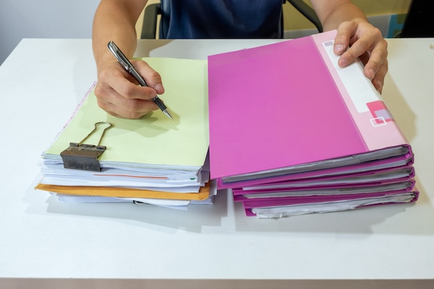 Man manager signant sur papier comptable avec fichier de pile sur le bureau