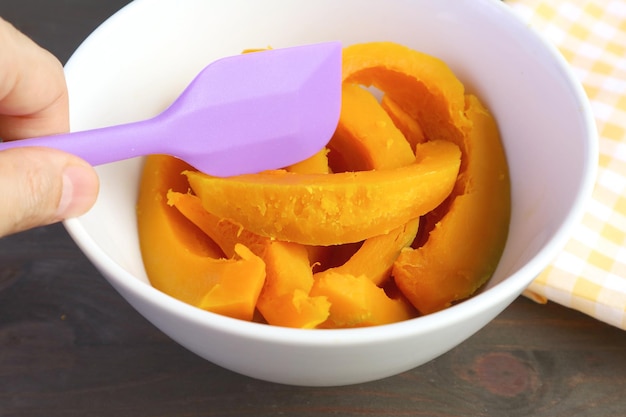 Man's Hand Holding Spatula pour la cuisson de la purée de citrouille maison dans un arc de mélange