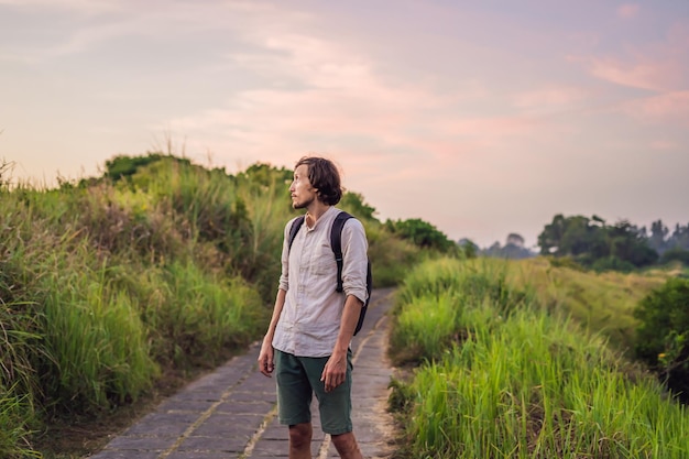 Man Traveler Campuhan Ridge Walk ou Artists Walk sentier sacré, île de Bali, Indonésie Au coucher du soleil. Sentier paysage palmiers verts tropicaux.