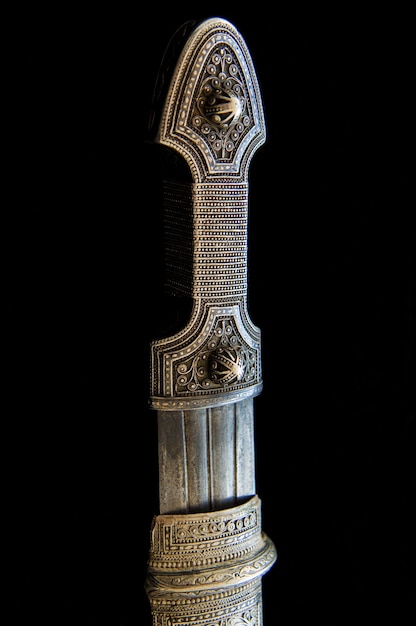 Le manche d'un poignard antique avec chasse artistique et gravure sur fond noir