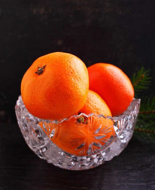 Mandarine dans un panier en métal avec une branche d&#39;un sapin de Noël sur fond noir