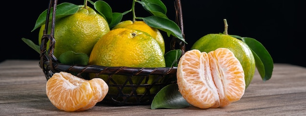 Mandarine mandarine verte fraîche avec des feuilles fraîches sur une table en bois foncé avec concept de récolte de fond noir.