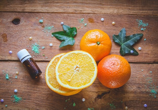 Photo mandarine, orange et bouteille essentielle sur fond de bois