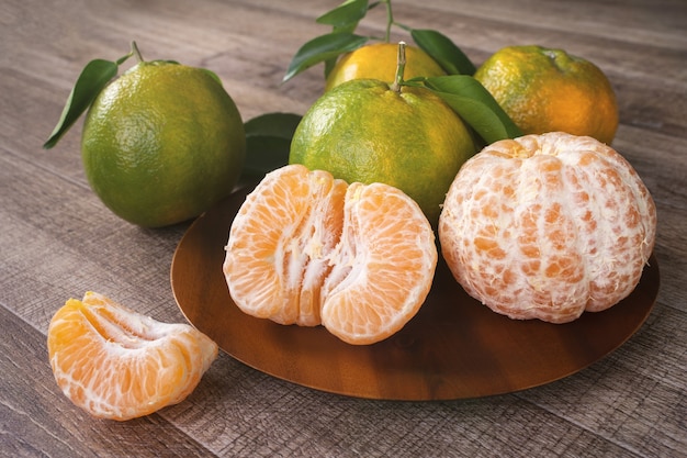 Photo mandarine verte fraîche avec des feuilles sur fond de table en bois foncé