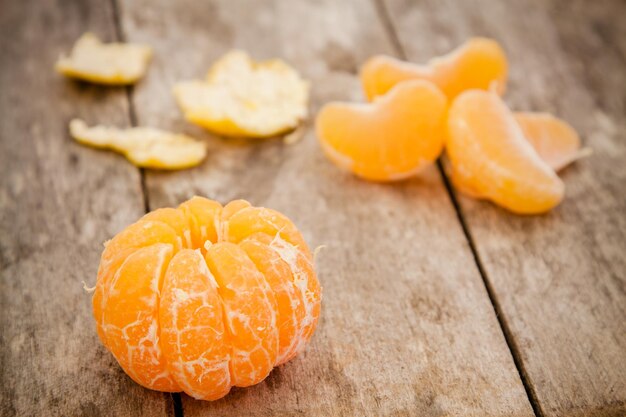 Mandarines biologiques fraîches et tranches pelées sur un fond de bois rustique