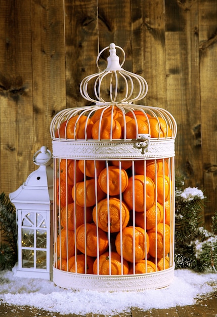 Mandarines en cage décorative, sur fond de bois