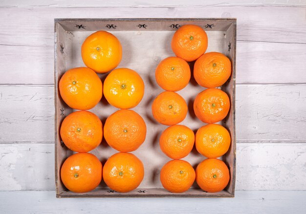 Mandarines et clémentines dans un vieux plateau en bois