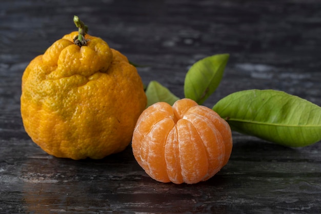 Mandarines ou clémentines avec des feuilles vertes sur fond noir