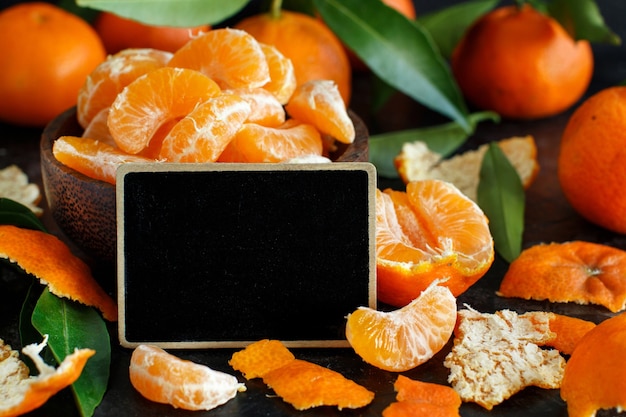 Mandarines dans un bol avec un petit tableau sur fond sombre