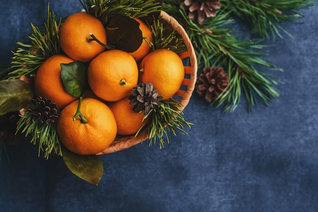 Mandarines dans un panier en bois et des pommes de pin et des branches