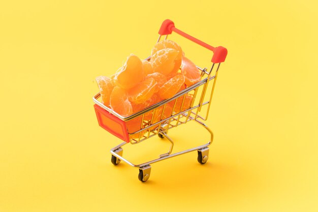 Mandarines dans un panier sur fond jaune, acheter un concept d'aliments sains