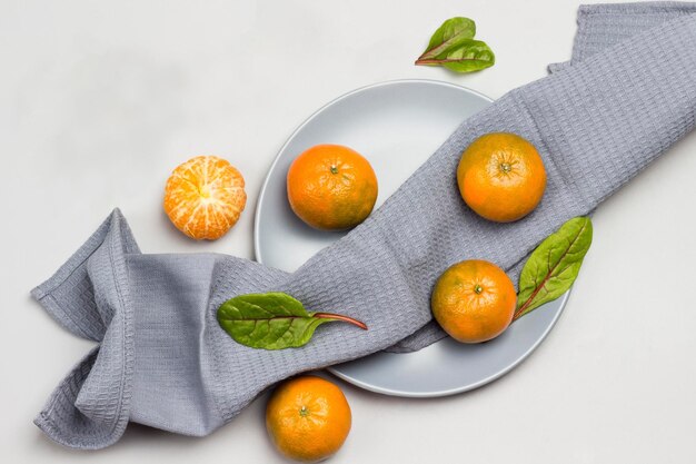 Photo des mandarines avec des feuilles de chard sur une serviette grise