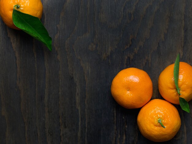 Mandarines avec des feuilles sur un fond en bois, vue de dessus