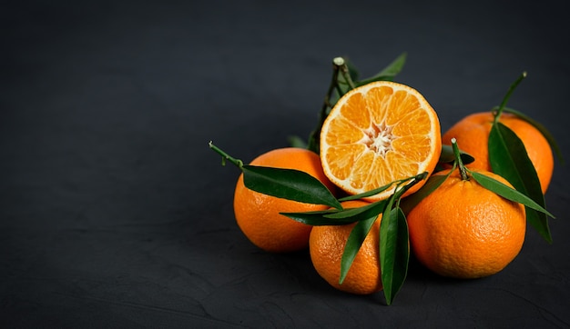 Mandarines avec des feuilles sur fond noir.