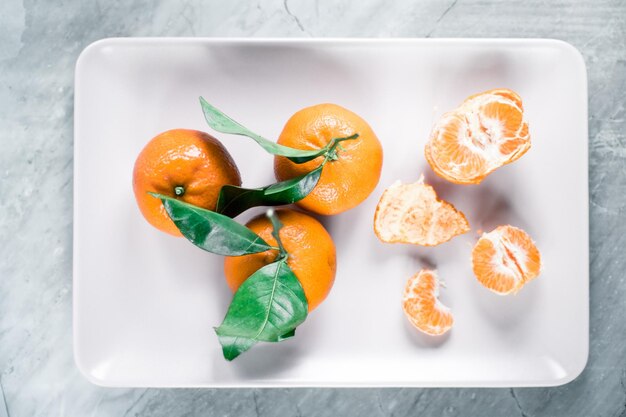 Mandarines avec des feuilles sur la plaque d'agrumes et concept de flatlay de saine alimentation