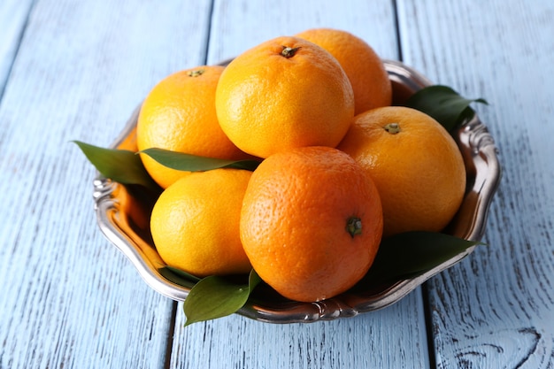 Mandarines avec feuilles sur plaque sur table en bois