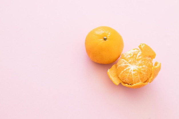 Mandarines avec feuilles et tranches sur fond rose