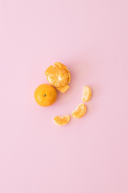 Mandarines avec feuilles et tranches sur fond rose