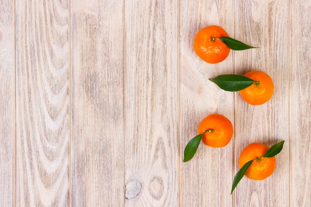 Mandarines avec des feuilles vertes sur fond en bois