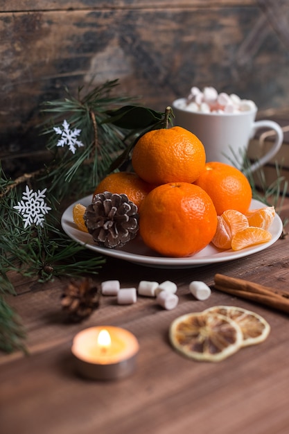 Mandarines fraîches sur une assiette avec des guimauves dans une tasse et cannelle