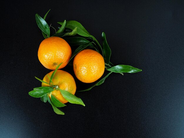 Mandarines fraîches avec des feuilles vertes sur fond noir Vue de dessus