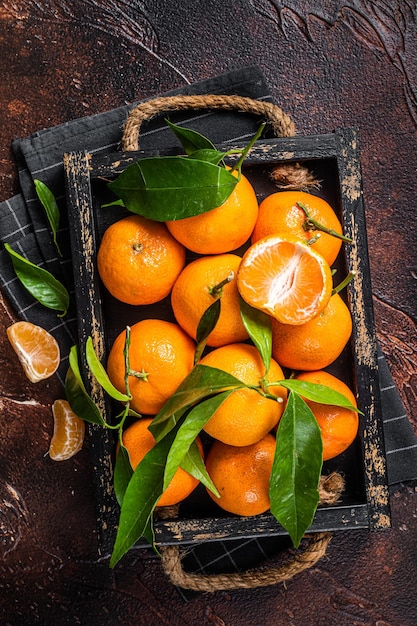 Mandarines fraîches ou fruits de mandarines avec des feuilles. Fond sombre. Vue de dessus.