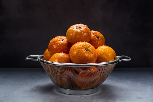 Photo mandarines fraîches juteuses dans une passoire en métal