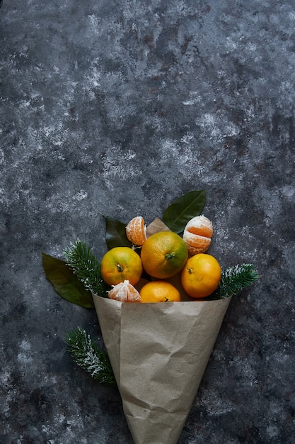 Mandarines juteuses avec des feuilles et des branches de sapin dans un sac en papier