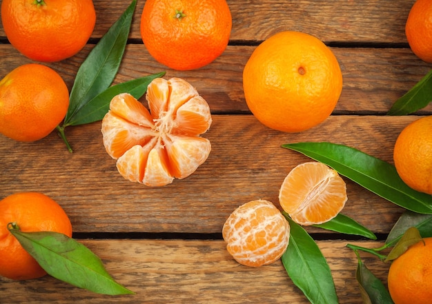 Mandarines mandarines juteuses et sucrées avec des feuilles sur fond de bois