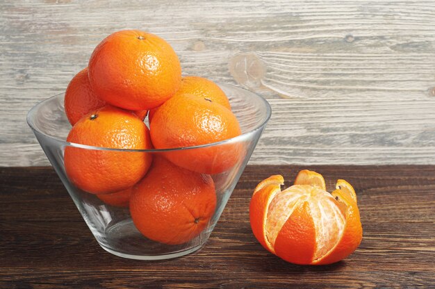 Mandarines mûres dans un bol en verre sur une table en bois rustique