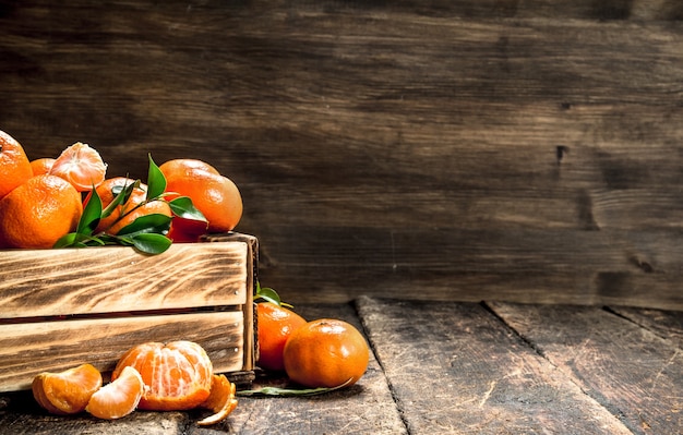 Mandarines mûres dans une vieille boîte sur table en bois.