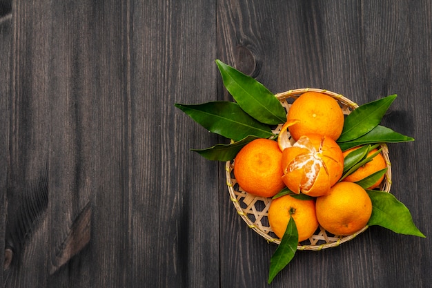 Mandarines mûres fraîches avec des feuilles dans le panier.