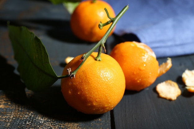 Mandarines mûres juteuses avec des feuilles sur une table en bois