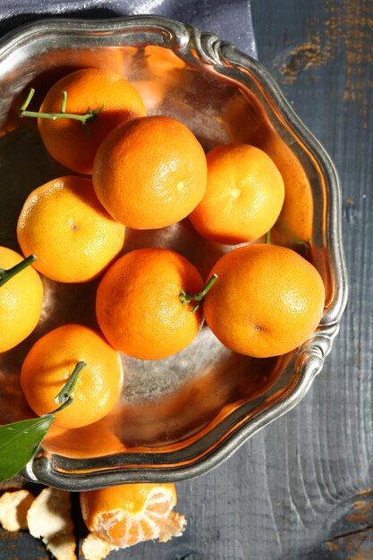 Mandarines mûres juteuses avec des feuilles sur une table en bois